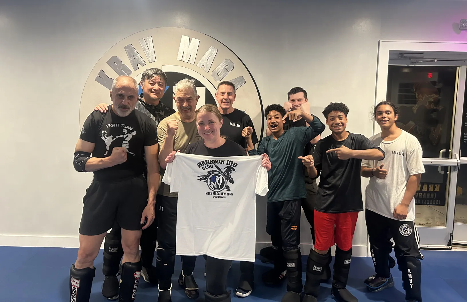 Teen Krav Maga students and instructors celebrating an achievement together during a self-defense class.