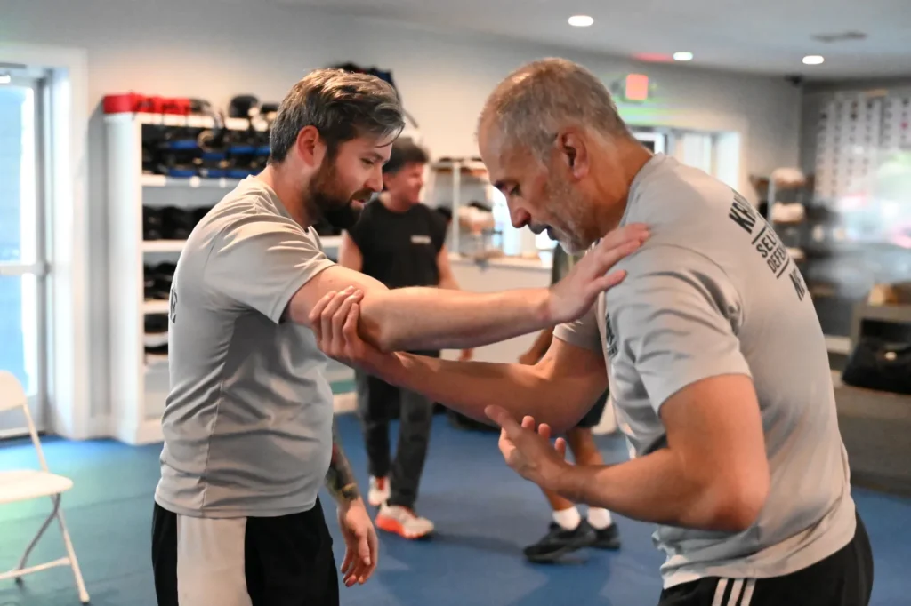 An instructor demonstrating arm control techniques during an adult Krav Maga self-defense session.